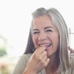 Woman holding glass of water taking pill